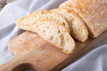 Close-up of bread slices on wooden serving board over napkin
