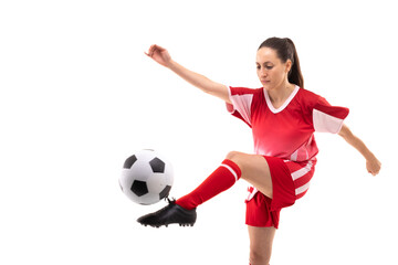 Caucasian young female soccer player kicking ball while playing soccer against white background