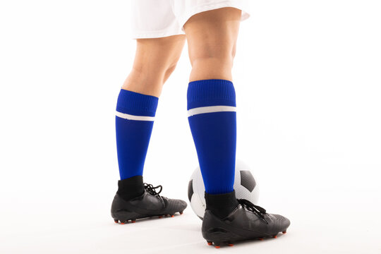 Low section of biracial young female player with soccer ball standing against white background