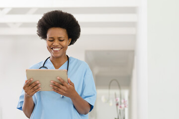 Happy african american mid adult female doctor using digital tablet in hospital