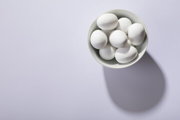 Overhead view of white eggs in bowl on table with empty space