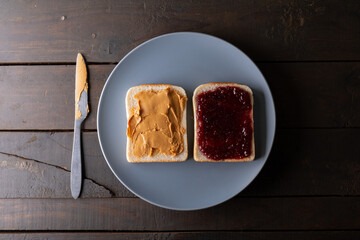 Directly above shot of open face peanut butter and jelly sandwich in plate on table with table knife