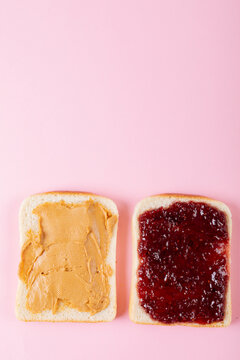 Directly above shot of open face peanut butter and jelly sandwich on pink background with copy space