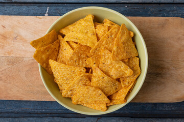 Directly above close-up shot of nacho chips in bowl on serving board at wooden table