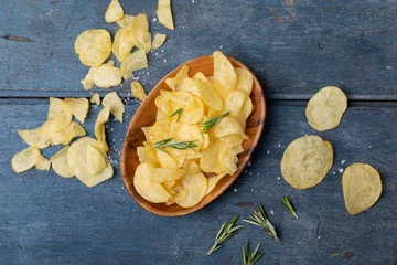 Poster Overhead view of potato chips in bowl with rosemary and salt on wooden table © WavebreakMediaMicro