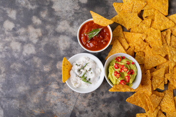 Overhead view of nacho chips with various dipping sauces served on table