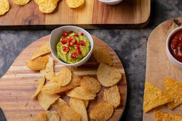 High angle view of chips with various salsa served on serving board at table