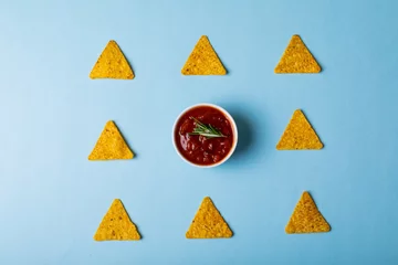 Foto op Aluminium Overhead view of red sauce with rosemary amidst nacho chips arranged on blue background © wavebreak3