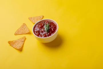 Foto op Canvas Red sauce with rosemary served in bowl with nacho chips on yellow background with copy space © WavebreakMediaMicro