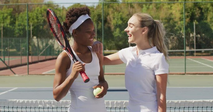 Video of happy diverse female tennis players holding rackets and talking