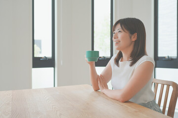 リビングで飲み物を飲んでリラックスする女性