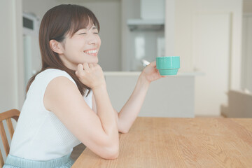 リビングで飲み物を飲んでリラックスする女性