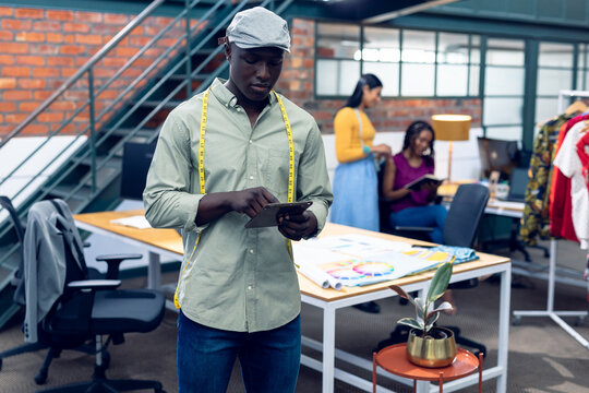 African american young male fashion designer using digital table while standing at workplace