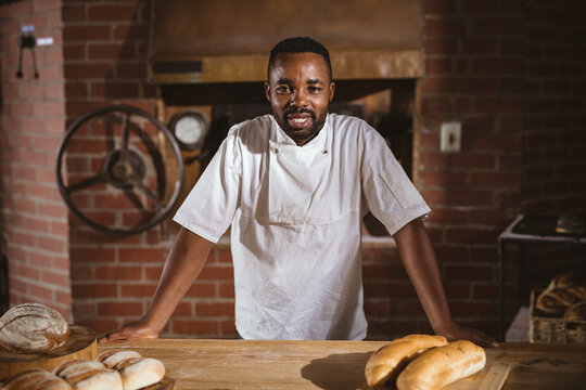 Portrait of confident smiling mid adult african american male baker standing in bakery