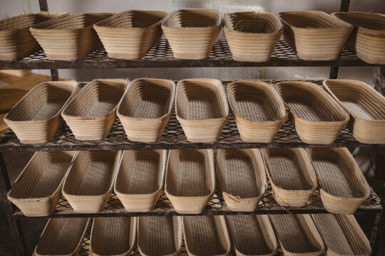 Full frame shot of wicker bread baskets arranged side by side on shelf in bakery