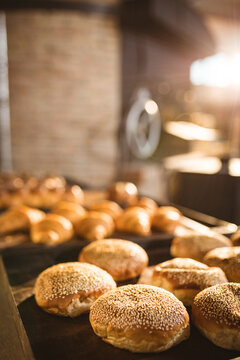 Close-up of sesame seeds buns in baking tray on table in bakery