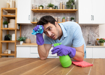 Tired man standing in the kitchen after cleaning house. Exhausted household concept	