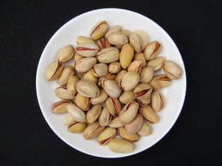 Pistachios on a plate on black background 