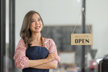 Shot of smiling Asian young sme small business owner wearing apron and standing white ipad and open...
