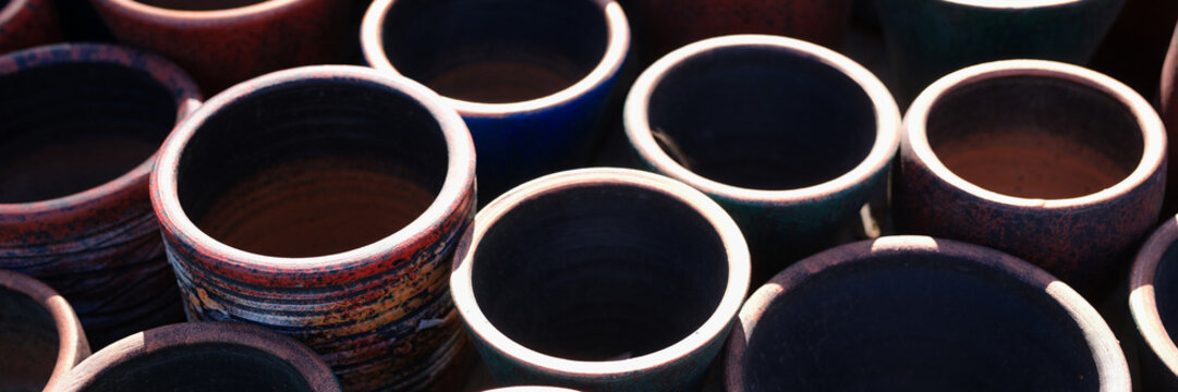 Lot of clay multicolored pots standing on shop window closeup background