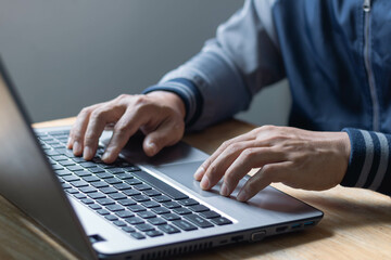 Closeup man hands typing on a computer laptop keyboard, businessman or student using laptop at home, online learning, internet marketing, investment and trading, working from home, freelance concept