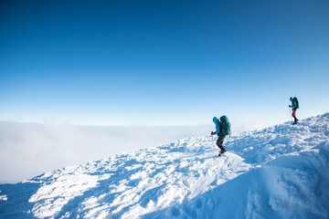 Fototapeta na wymiar Two women with backpacks walk in snowshoes in winter trekking