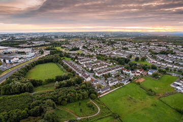 Aerial view on high dense residential area at sunset. House estate by a small park with green trees...