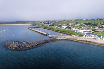 Mullaghmore pier and marina with small fishing boats and yachts. County Sligo, Ireland. Popular travel area with water sports and great nature sightseeing. Aerial view. Warm sunny day. Cloudy sky.