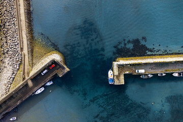 Camper vans on a small pier and fishing boat in the ocean. Top down aerial view. Travel and holiday...