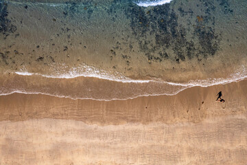 Aerial view tourist walking on a sand of Streedagh beach in county Sligo, Ireland. Beautiful nature scene with warm yellow sand and blue ocean. Popular tourist area. Warm sunny day.