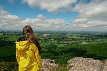 Teenager girl hiker in yellow jacket on a trip in a mountains. Beautiful nature scenery view in the background. Travel and tourism concept. Active lifestyle.