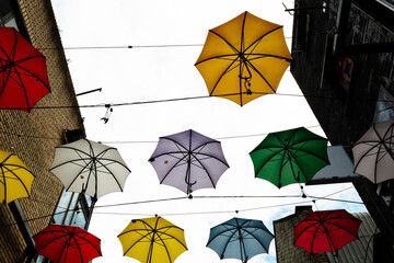 Open multi color open umbrellas used as an original decoration element in a street. Design idea and...