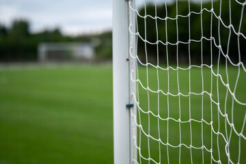 Side of football of soccer goal post with net in focus. Field out of focus. Sport background and equipment. © mark_gusev