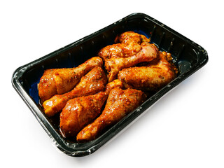 Corn fed chicken wings and drumstick in Asian style spicy marinated with herbs in a black plastic tray. Uncooked chicken meat product for barbecue or frying. Isolated on white.