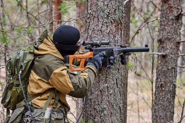 Naklejka premium a man in the forest shoots from a machine gun