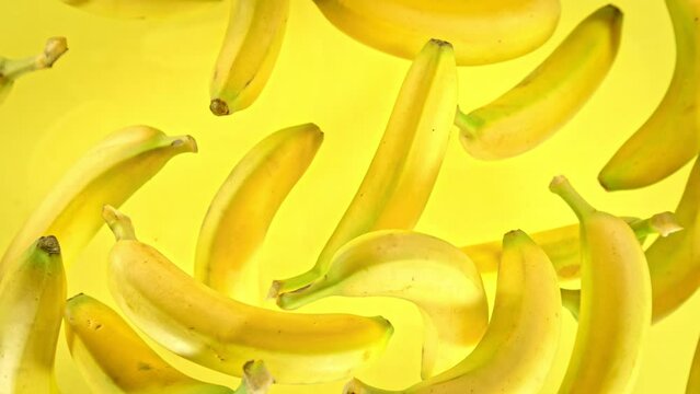 Super Slow Motion Shot of Fresh Bananas on Yellow Background Flying Towards Camera at 1000fps.