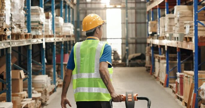 Asian man, manual worker use hand to pull, drag or lug pallet jack in warehouse, store for management, organization box on shelf or racking. Concept for industry, distribution, inventory, shipping.
