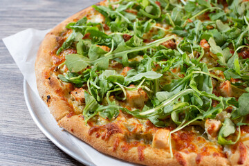 A view of a chicken and arugula pizza.