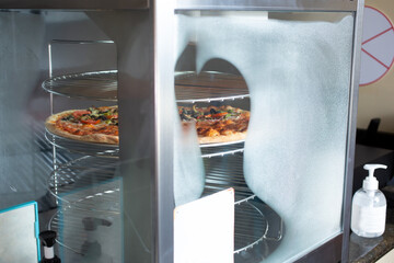 A view of a pizza inside a pizza warming appliance, seen at a local restaurant.