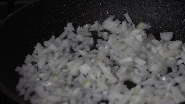 Chopped onions fry in a pan in vegetable oil close-up, fry stirring