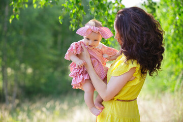Obraz premium A brunette woman, a young mother with a baby girl walking in the park
