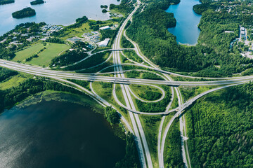 Aerial view of highway and overpass road with green woods and blue lakes in Finland.
