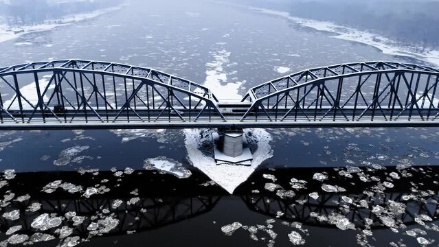 Snowy bridge over river with floe in winter