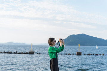 Fototapeta na wymiar 海で撮影するカメラ女子