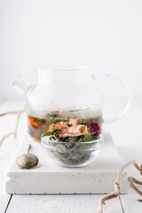 Herbal tea. Detox. Dry and brewed tea in a glass teapot on a white wooden background