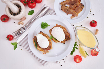Tasty eggs Benedict, hollandaise sauce and aspargus covered with bacon
