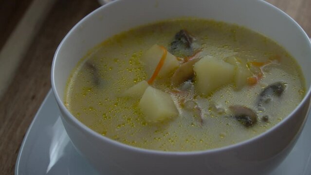 Adding some herbs in a Mushroom soup in a white bowl
