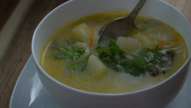 Mushroom soup in a bowl, stirring with a tablespoon