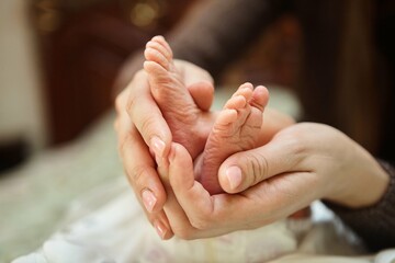 Mother's hand holding the legs of her newborn baby