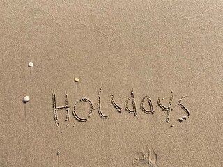 on the beach is carved with letters in the smooth sand the writing holidays